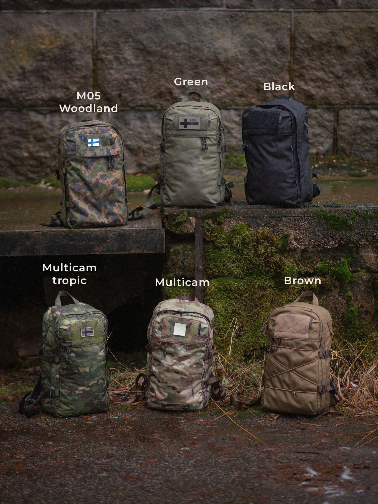 Six differently colored Savotta Niukka backpacks (M05 Woodland, green, black, Multicam tropic, Multicam and brown) on a stone surface outside.