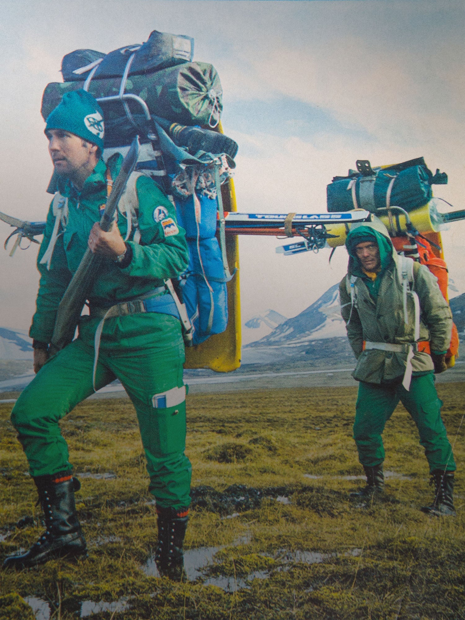 Two people in green outdoor wear carrying large Savotta packs in a mountainous landscape