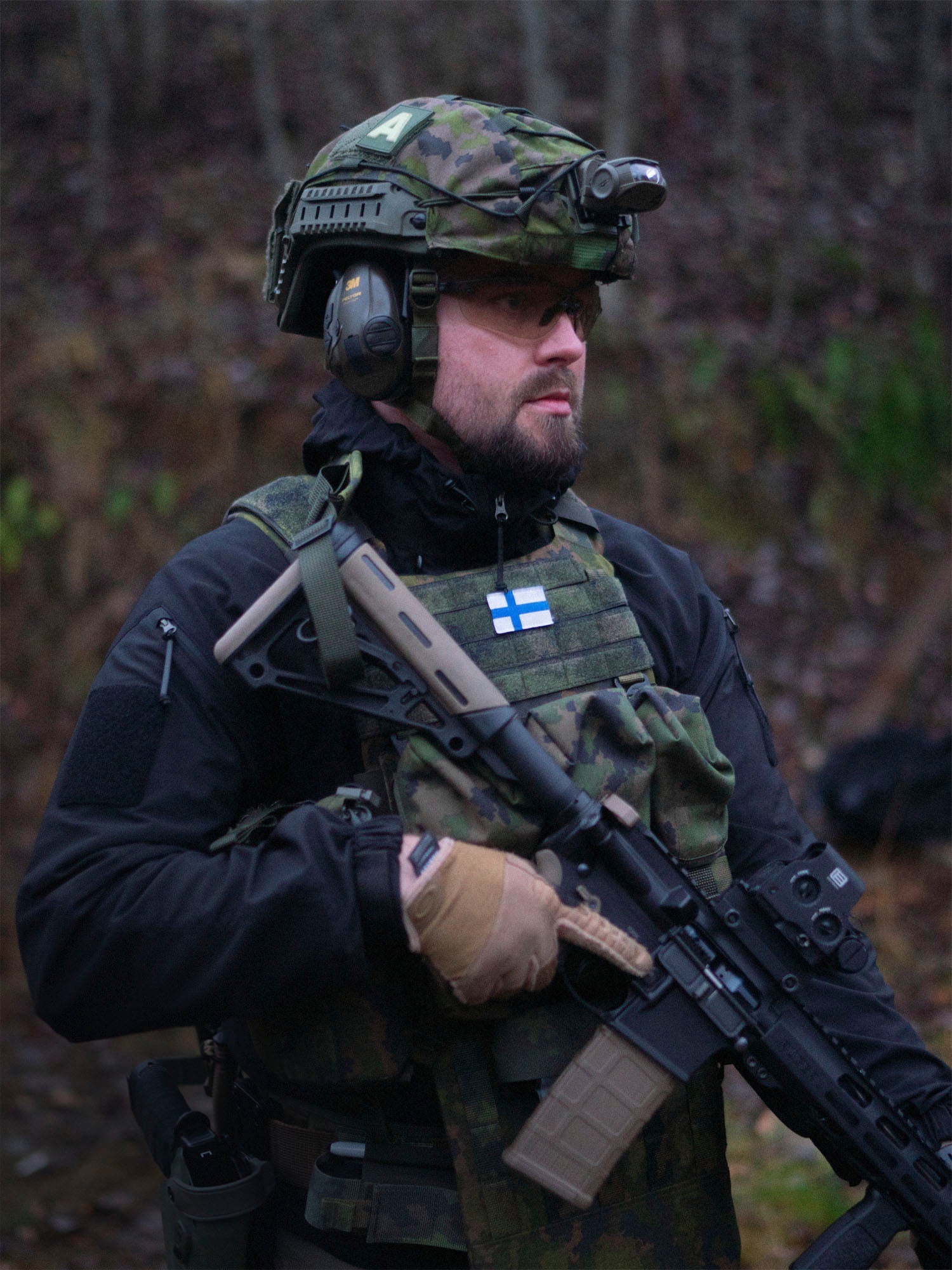 Antti Peltoniemi, the Sales Manager of Savotta in tactical gear with a rifle in a forest setting