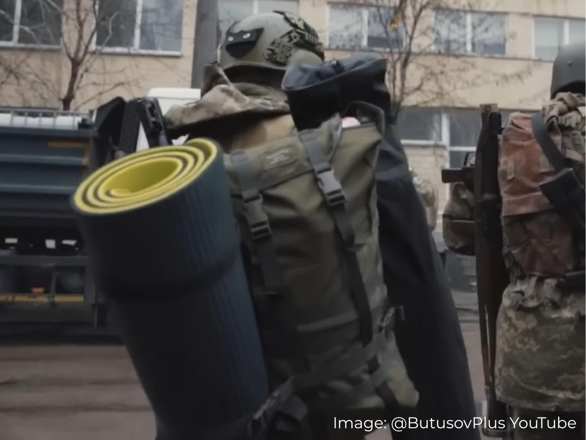 Ukrainian soldier in military gear with a Savotta Kahakka backpack and rolled-up mat attached in an urban setting