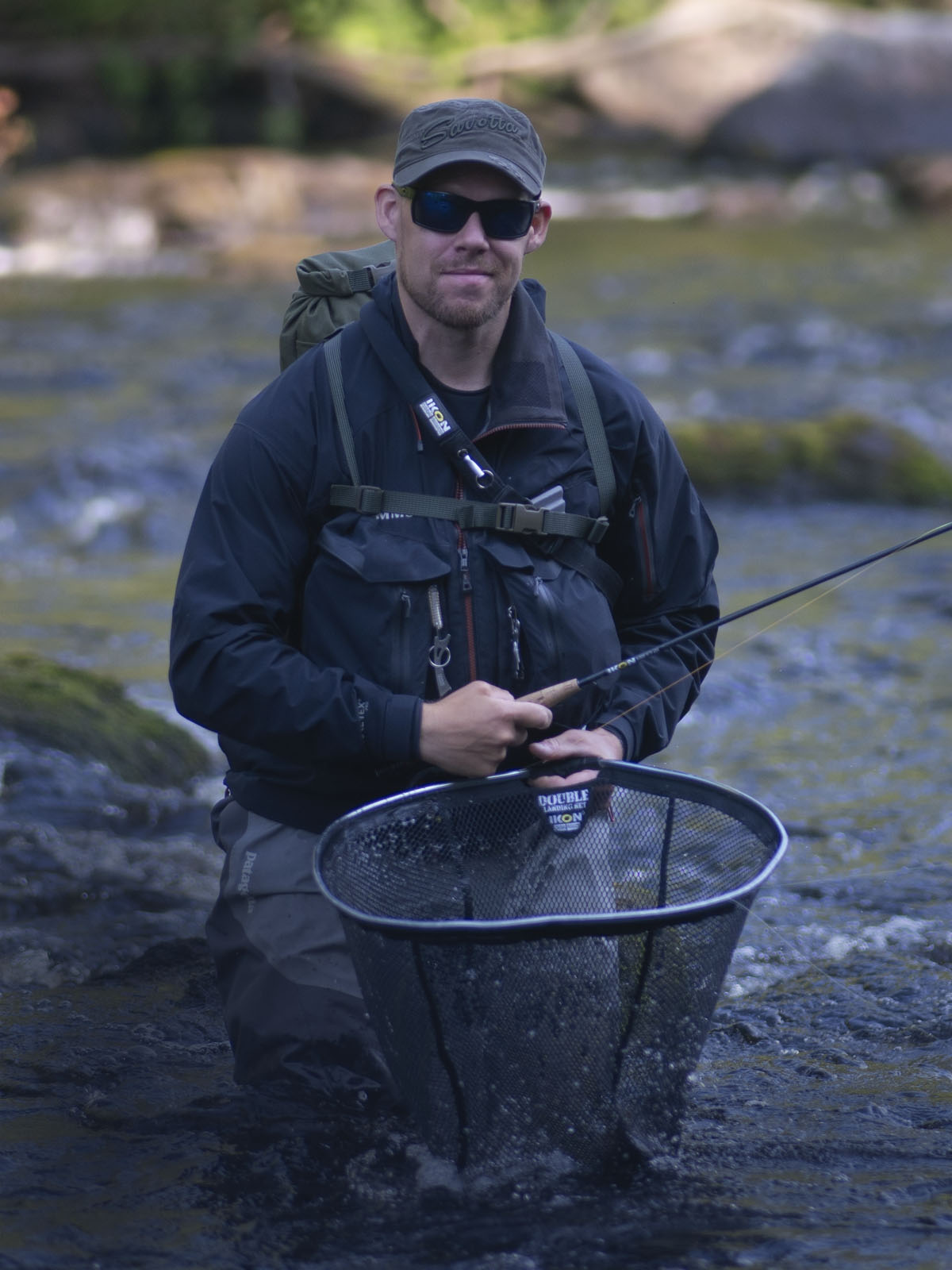 Jyri Yläpöntinen, the Sales Manager of Savotta fishing in a river with a net and backpack
