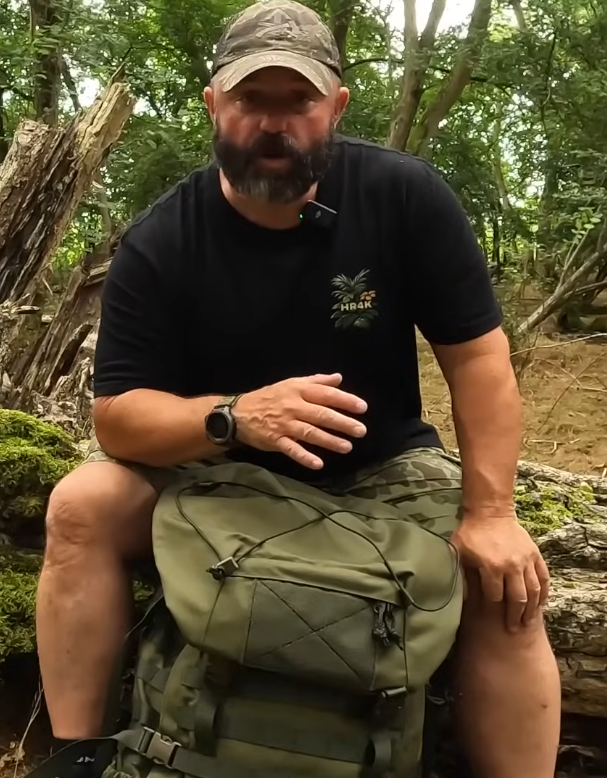 Man sitting on a log in a forest with a Savotta Kantamus 60L between his legs