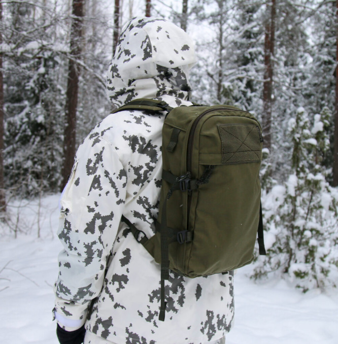 Person in winter camouflage clothing with a green Savotta Niukka backpack in a snowy forest