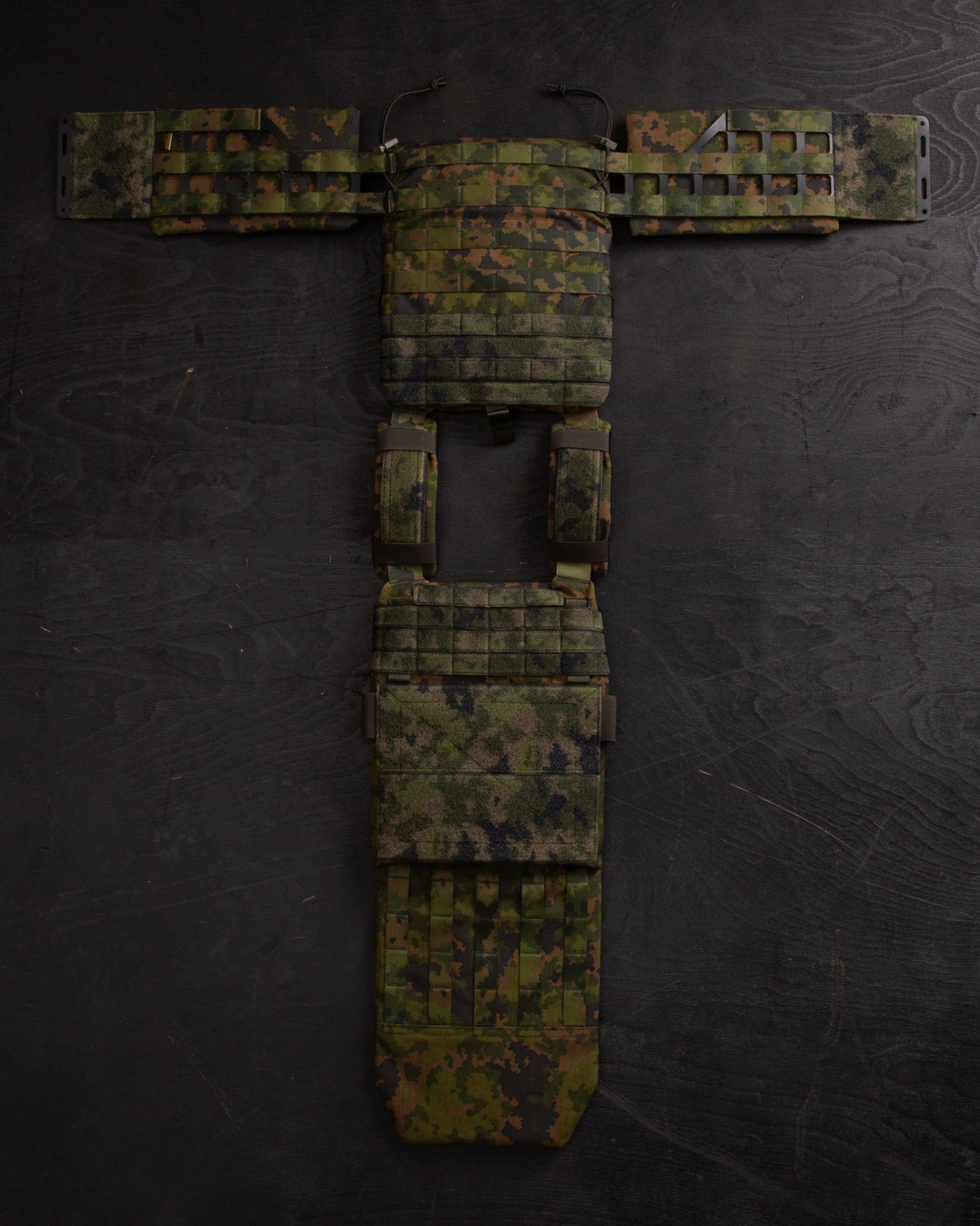 Savotta Varjelus groin flap attached to the opened up Savotta plate carrier on a dark wooden surface