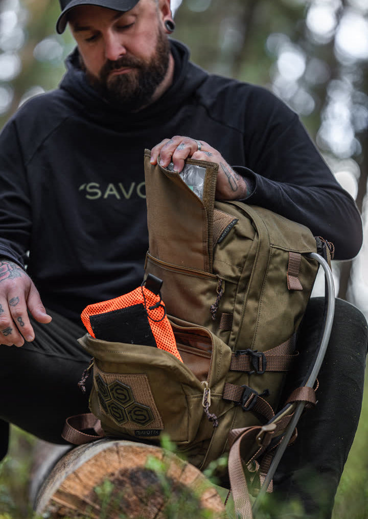 Man holding a Niukka 20L with a Suur-Kukkaro hip pack strapped to it outdoors