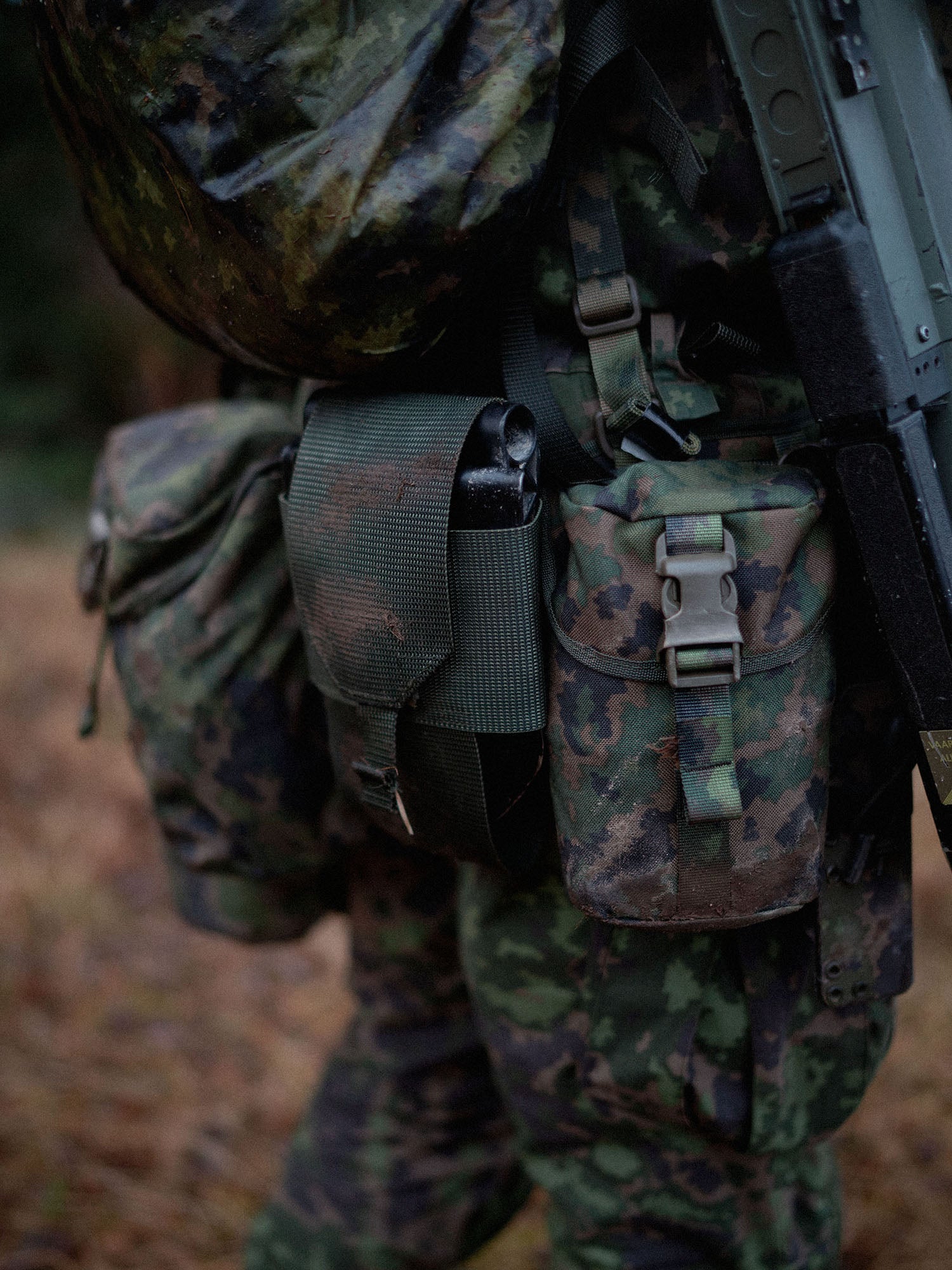 Camouflage military uniform with a Savotta Lidded GP pouch 3x4, other pouches and a rifle.