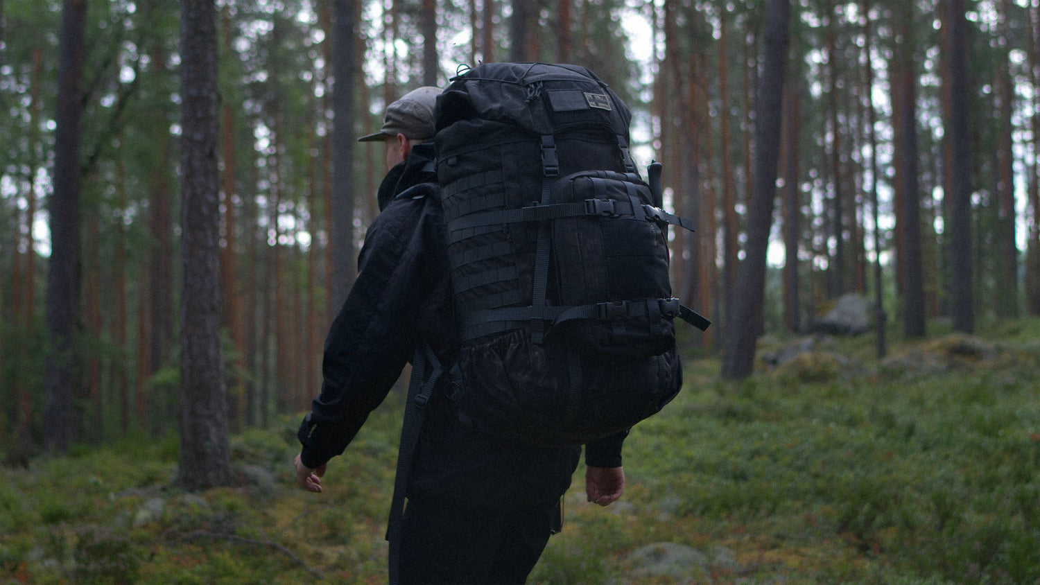 Person with a black Kantamus 60L backpack with a Savotta Askare hip pack attached walking through a forest