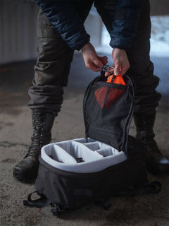 Person attaching a Savotta trinket pouch inside a black Savotta Niukka 20Lbackpack on a concrete floor.