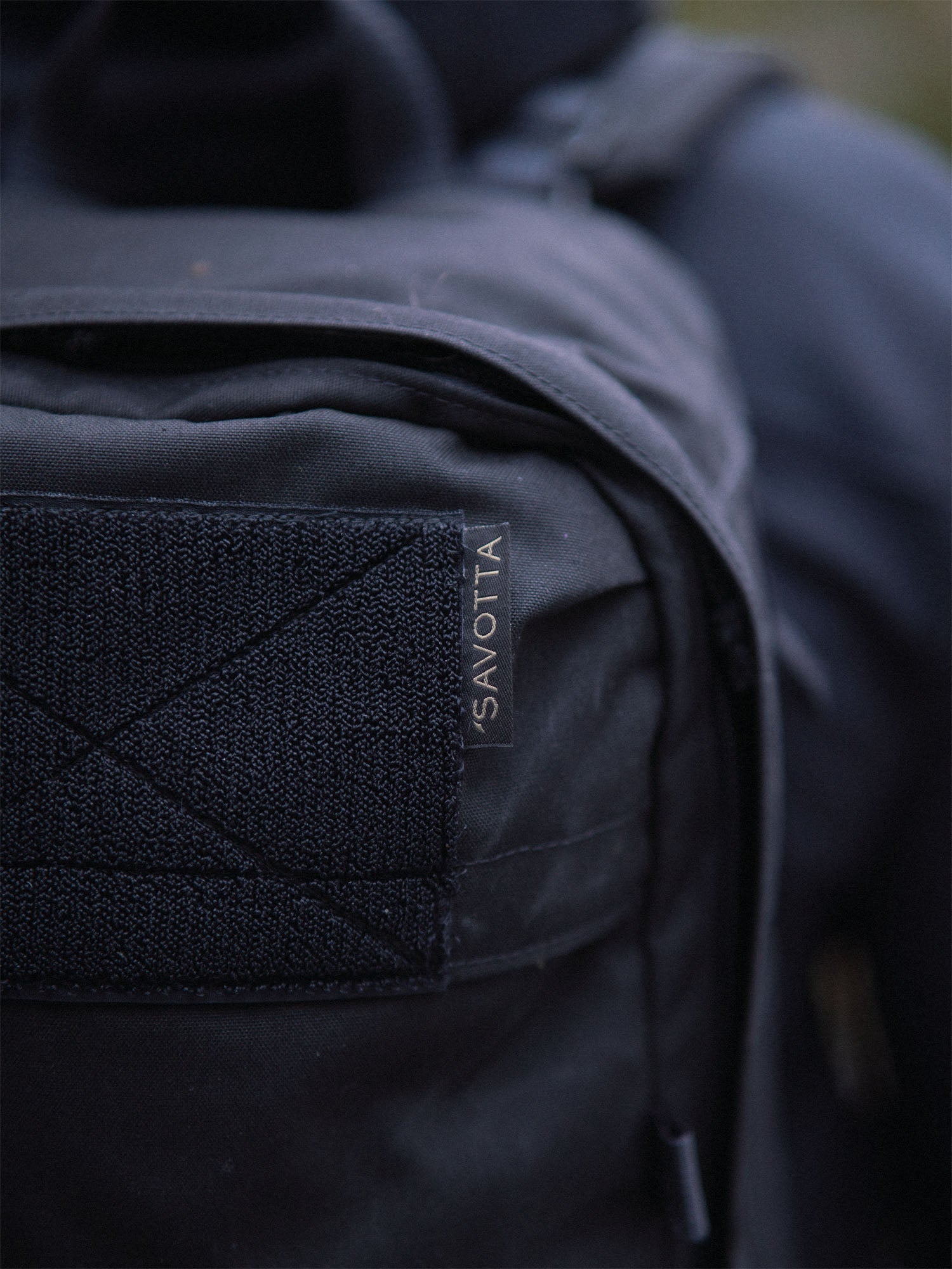 Close-up of a black Savotta Niukka 20L backpack on a person's back.
