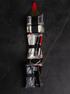 Filled Savotta S-IFAK insert laid open on a dark wooden surface