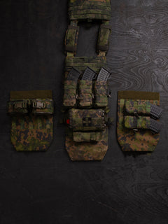 Three different setups you can do with a Savotta Varjelus groin flap. The Savotta plate carrier is being spread out on a dark wooden background. There are different Savotta mag pouches and Savotta S-IFAK horizontal mount attached to the groin flaps.