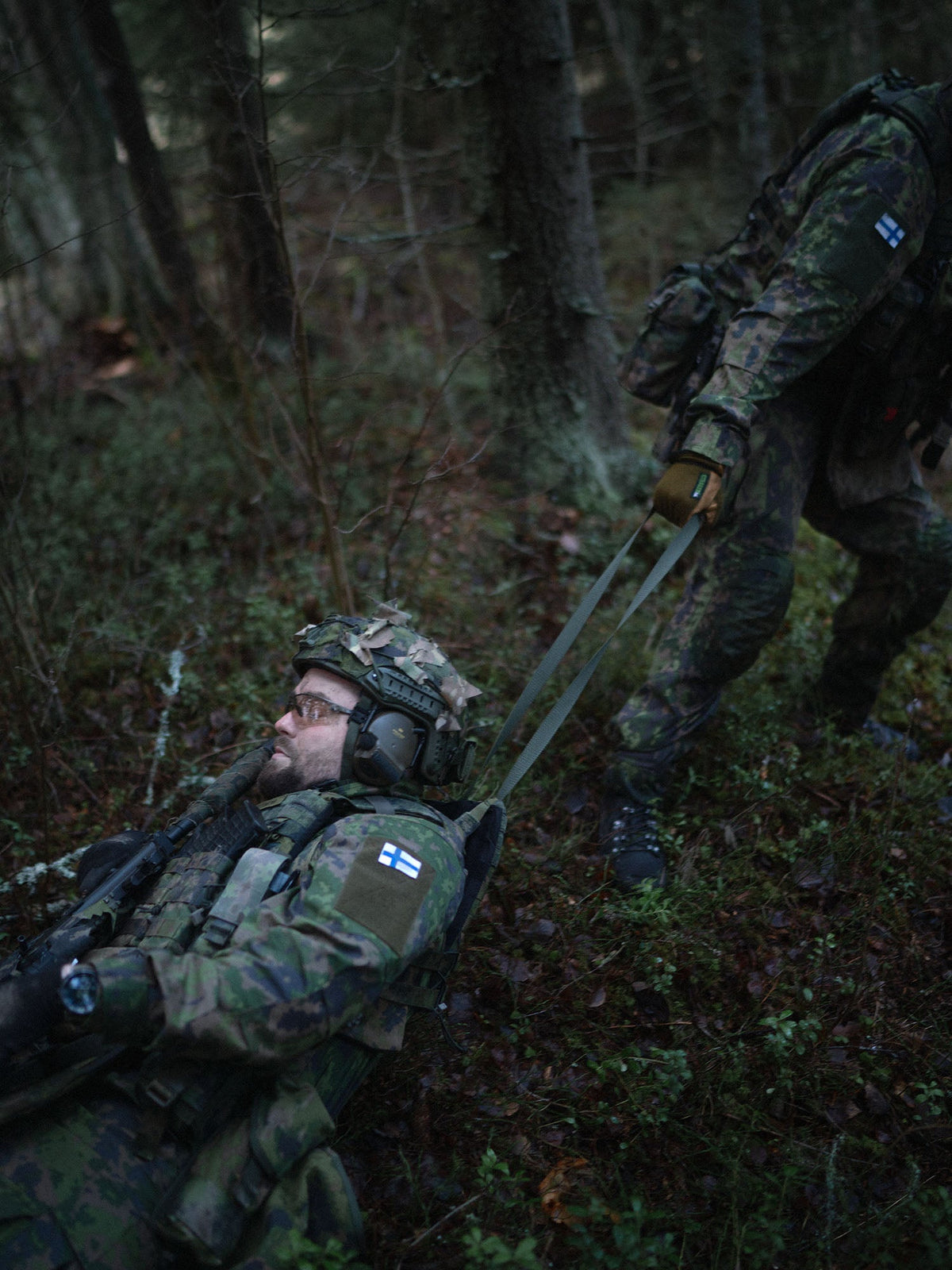 A soldier dragging a wounded soldier using a drag handle of a Savotta Varjelus plate carrier
