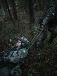 A soldier dragging a wounded soldier using a drag handle of a Savotta Varjelus plate carrier
