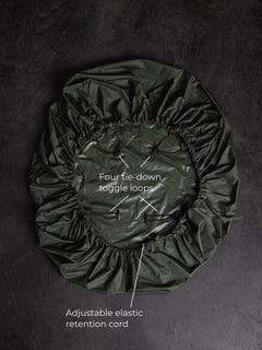 Savotta backpack cover 50L lying on a dark wooden surface with labels