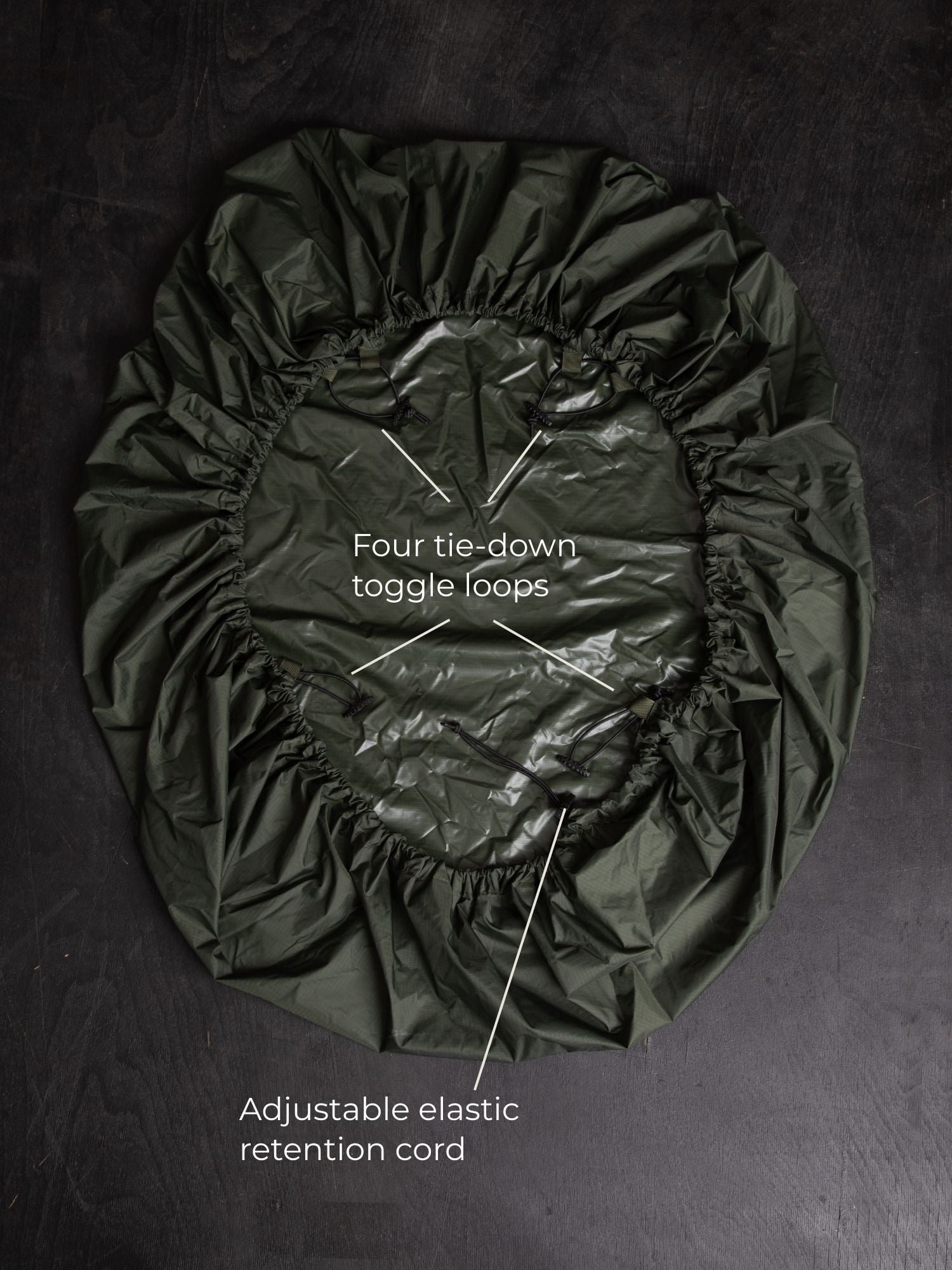 Savotta backpack cover 80L lying on a dark wooden surface with labels