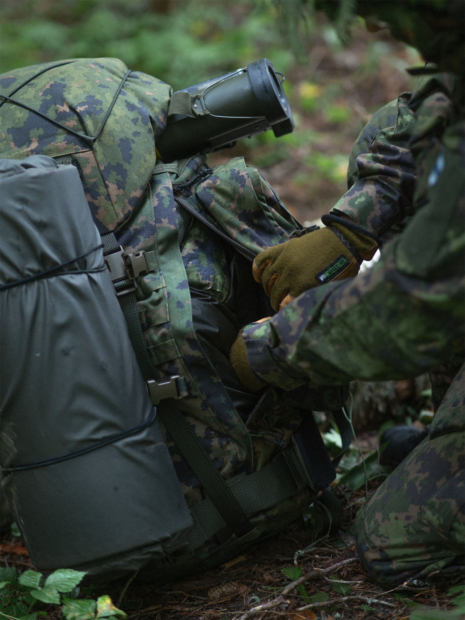 Soldier opening the side zipper pouch of a Savotta Kantamus 60L in a forest