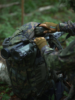 Soldier putting an item into a hat zipper pouch of a Savotta Kantamus 60L in a forest setting