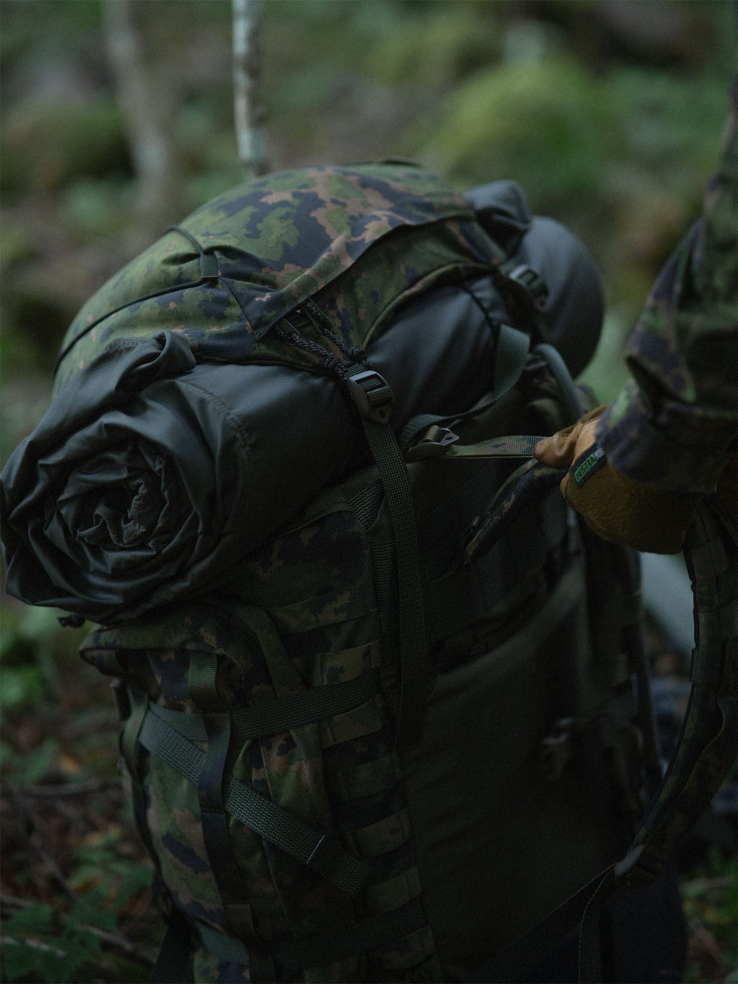 Rolled-up Savotta FDF sleeping pad under the hat of a Savotta Kantamus 60L in a forest