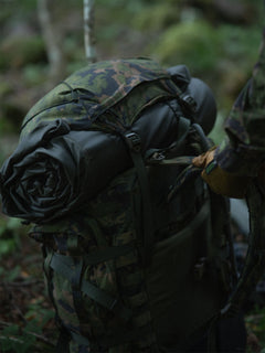 Rolled-up Savotta FDF sleeping pad under the hat of a Savotta Kantamus 60L in a forest