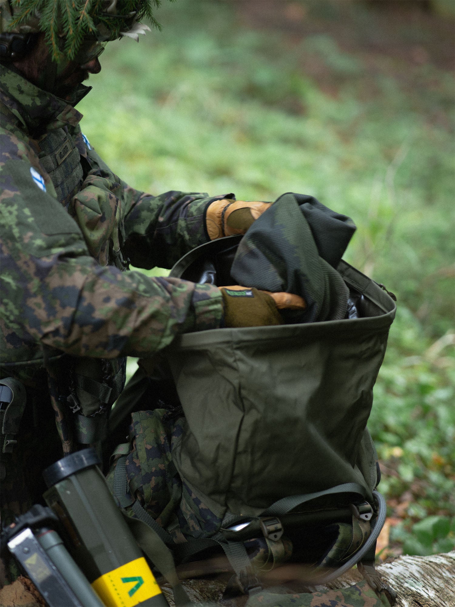 Soldier taking gear out of the opened rolltop closure of the Savotta Kantamus 60L in a forest