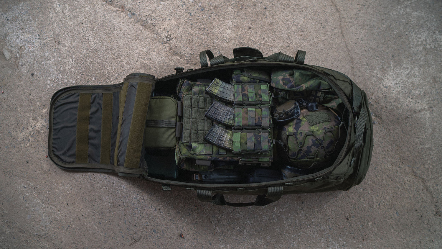 An opened Savotta Keikka bag showing all the gear you can fit in it, on a rocky surface.
