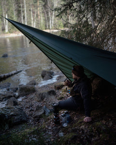 Person camping by a lake with a Savotta Laavu tarp as shelter