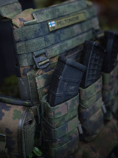 Close-up of a Savotta Varjelus plate carrier with mag pouches attached, in a forest setting