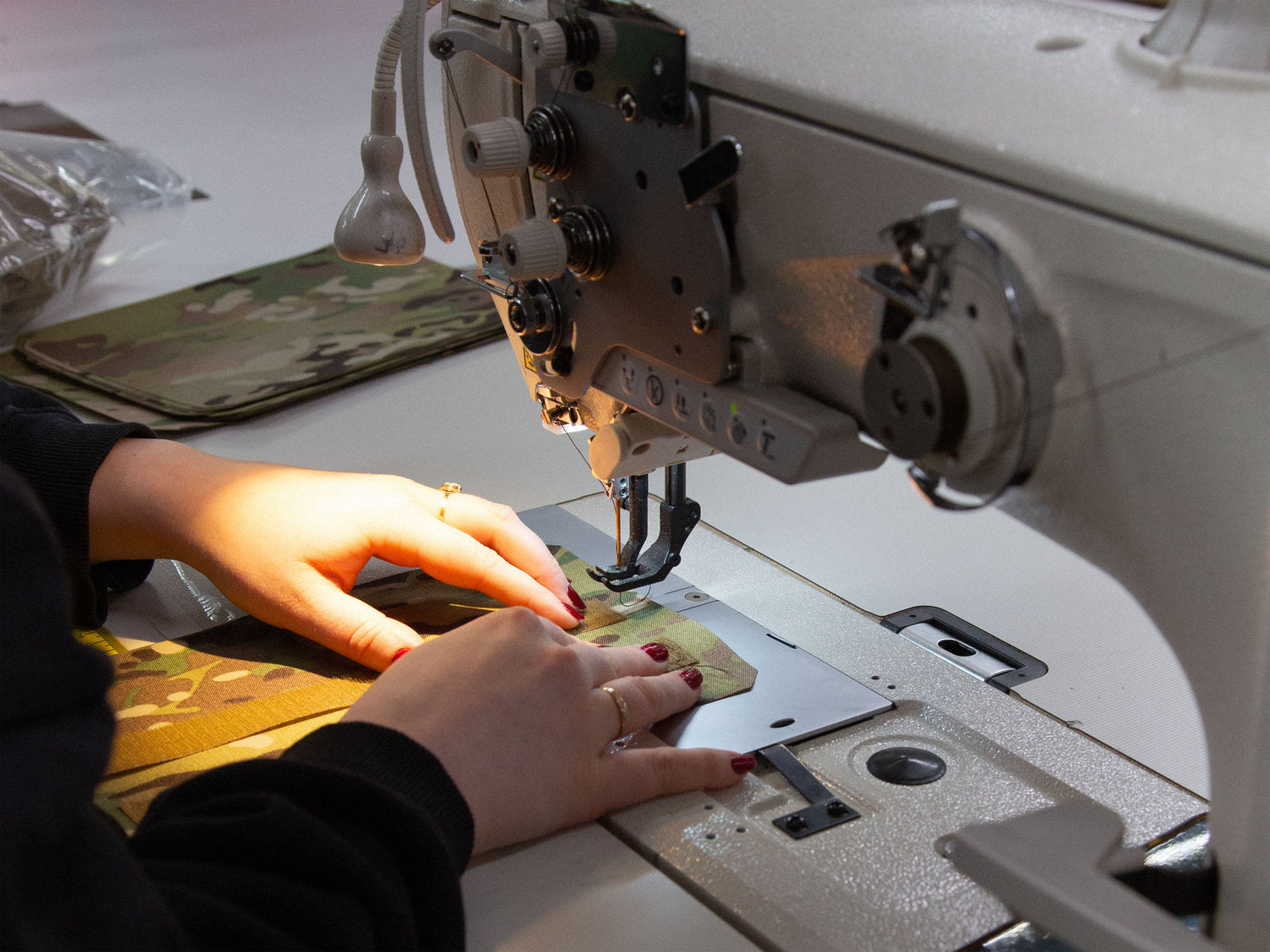 Person sewing the Savotta Varjelus plate carrier with a sewing machine in a workshop setting