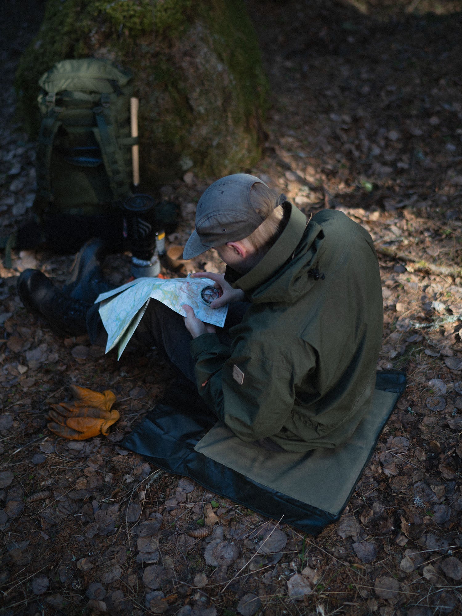 Person in a forest setting, sitting on Savotta sitting pad with a map and compass.