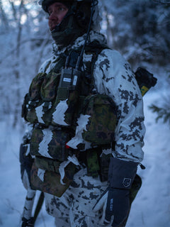 Person in winter camouflage gear with a Savotta plate carrier standing in a snowy forest