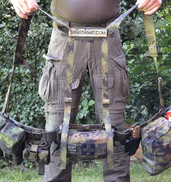 Person holding Savotta Valjas combat belt and H-Harness attached together. There are multiple pouches attached to the belt.